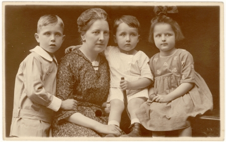 Portrait photographique de couleur sépia d'une femme avec trois jeunes enfants, posant ensemble  et étant habillés de manière formelle.