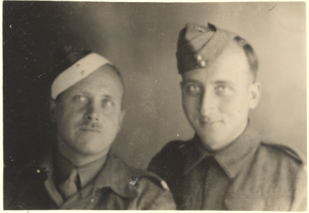 Photo en noir et blanc de deux hommes portant des uniformes militaires souriant à la caméra. L'homme à gauche porte une moustache.