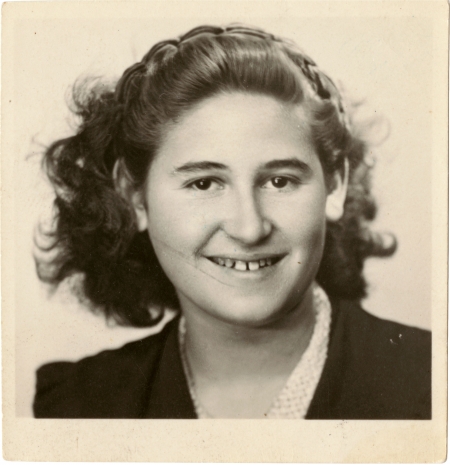 Photo de passeport en noir et blanc d'un jeune adolescente souriant à la caméra. Elle a des cheveux bruns ondulés jusqu'aux épaules.