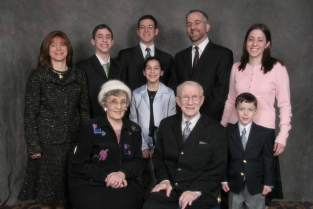 Photo en couleur prise en studio de neuf personnes d'une même famille rassemblées en deux rangées et souriant à la caméra.