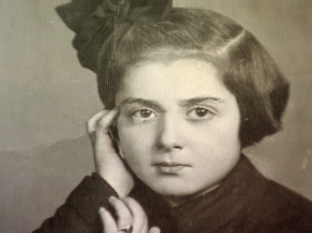 Portrait photographique d'un jeune fille regardant la caméra. Elle a la tête appuyée sur sa main et elle porte une boucle dans ses cheveux bruns courts.