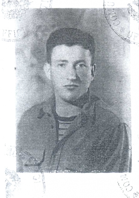 Black-and-white identity photograph of a young man, pictured form chest up, looking at the camera. He has dark brown hair, and wears a collared shirt over a striped t-shirt.