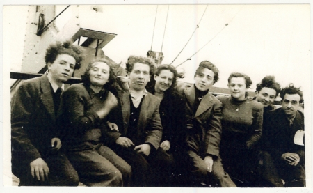 Photo d'un groupe de huit jeunes adultes, hommes et femmes, assis ensemble sur le pont  d'un navire.