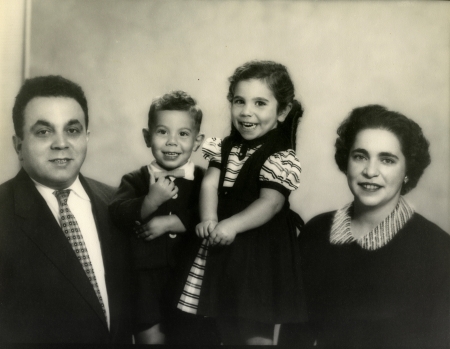 Photo en noir et blanc d'un homme et d'une femme avec deux jeunes enfants, tous souriant à la caméra.