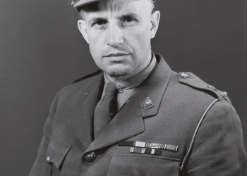 Black-and-white portrait photograph of a man, visible from his waist up, wearing a military suit.