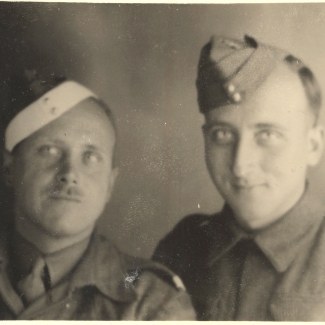 Photo en noir et blanc de deux hommes portant des uniformes militaires souriant à la caméra. L'homme à gauche porte une moustache.