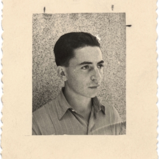 Black-and-white photograph with a large white border of a young man looking towards the right of the camera. His hair is combed back and he wears a collared shirt.