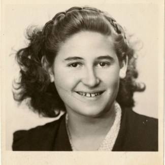 Photo de passeport en noir et blanc d'un jeune adolescente souriant à la caméra. Elle a des cheveux bruns ondulés jusqu'aux épaules.