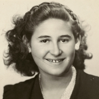 Black-and-white passport photograph of a young teenage woman smiling at the camera. She has wavy, dark brown, shoulder-length hair.