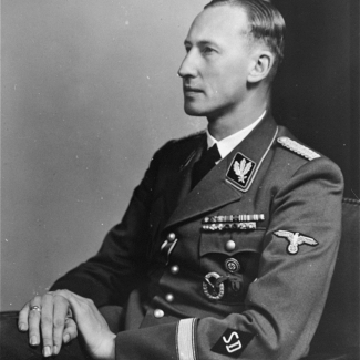 Black-and-white portrait photograph of a man looking towards the left of the camera, visible from his waist up, wearing a military suit.