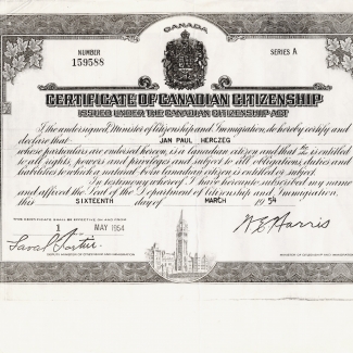 Black-and-white photocopy of a document with elaborate bordering that includes maple leaves and an illustration of the Canadian Parliament on the bottom. The certificate has italicized writing and two signatures.