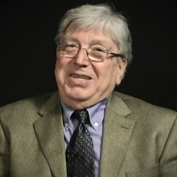 Screenshot of Holocaust survivor Paul Herczeg video testimony. He is sitting in front of a black background, and looking to the left of the camera. The camera shows his face and shoulders.