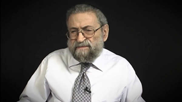 Screenshot of Holocaust survivor Joseph Lazar video testimony. He is sitting in front of a black background, and looking to the left of the camera. The camera shows his face and shoulders