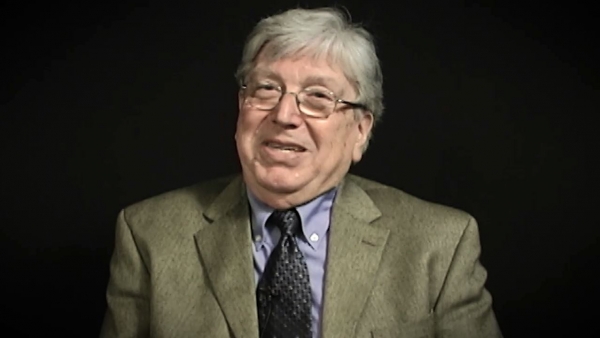 Screenshot of Holocaust survivor Paul Herczeg video testimony. He is sitting in front of a black background, and looking to the left of the camera. The camera shows his face and shoulders.