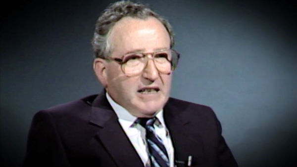 Screenshot of Holocaust survivor Moishe Kantorowitz video testimony. He is sitting in front of a dark background, and looking to the left of the camera. The camera shows his face and shoulders.